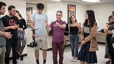 Professor Broderick Fox speaks animatedly with students in a MAC classroom