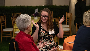 A young alumnus talks animatedly with an older alum