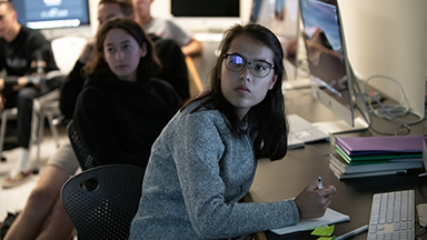 Two students sitting at computers look attentively past the camera
