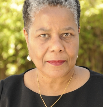 Portrait of Greta Mandell, she is pictured outside with greenery behind her